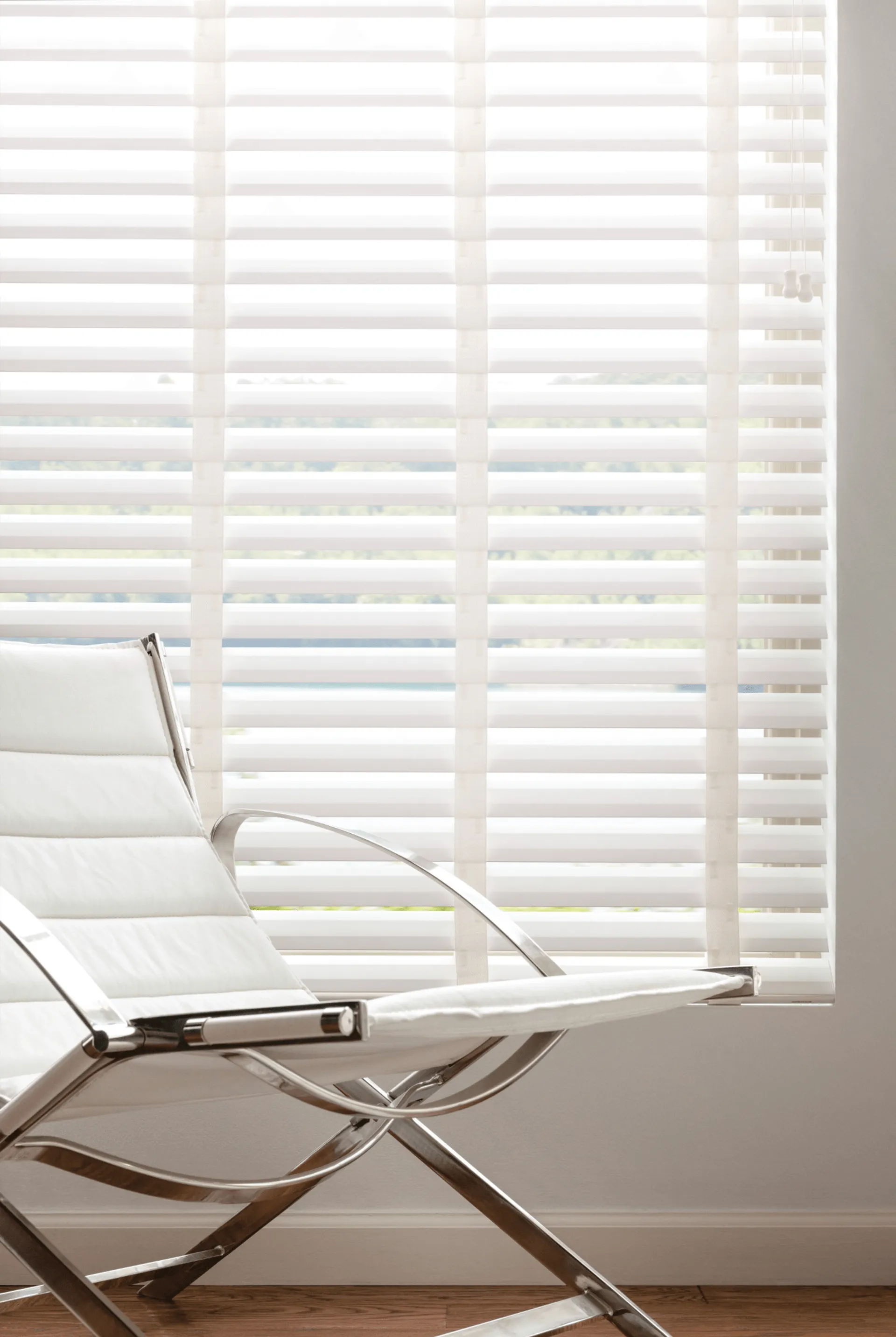 Soft natural light filtered through white horizontal blinds beside a reading chair